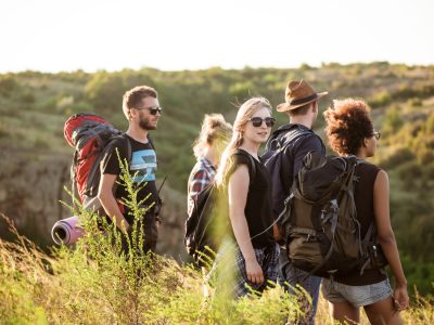 Young friends with backpacks enjoying view, traveling in canyon. Copy space.